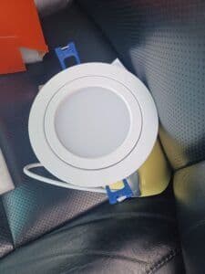 Round LED ceiling light fixture on a leather seat, showcasing modern design and wiring.