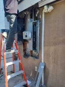 Electrician working on an electrical panel installation outside a building.