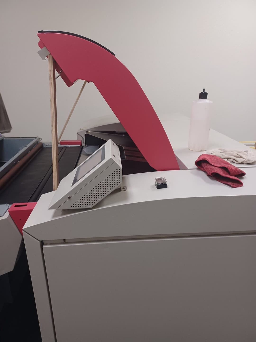 Laser cutting machine with control panel and cleaning supplies on workspace.