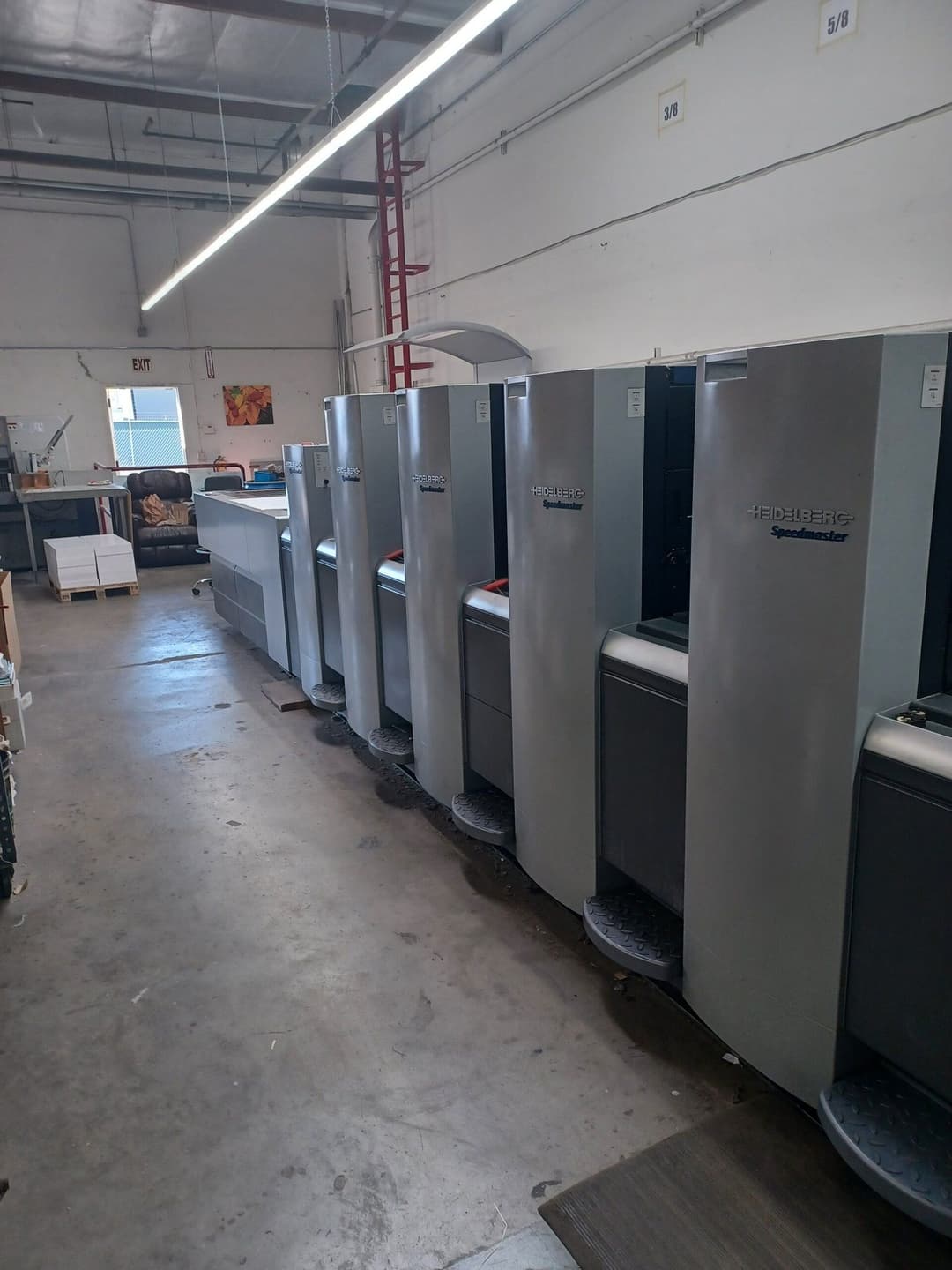 Commercial printing equipment line in a spacious workshop setting.