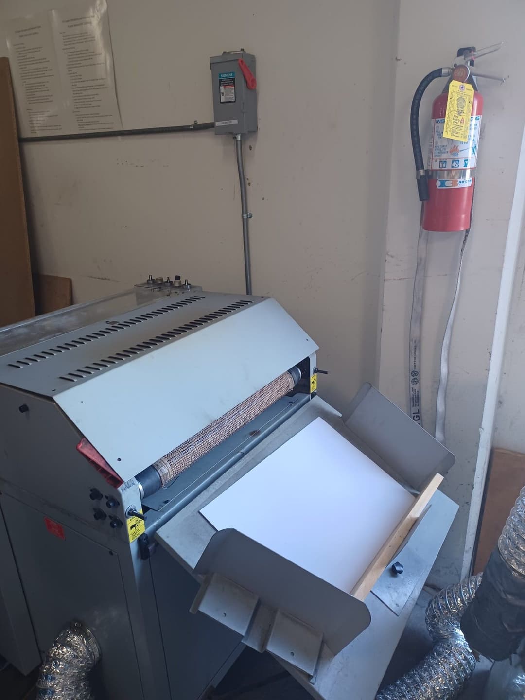 Paper laminating machine with control panel, safety fire extinguisher, and ventilation.