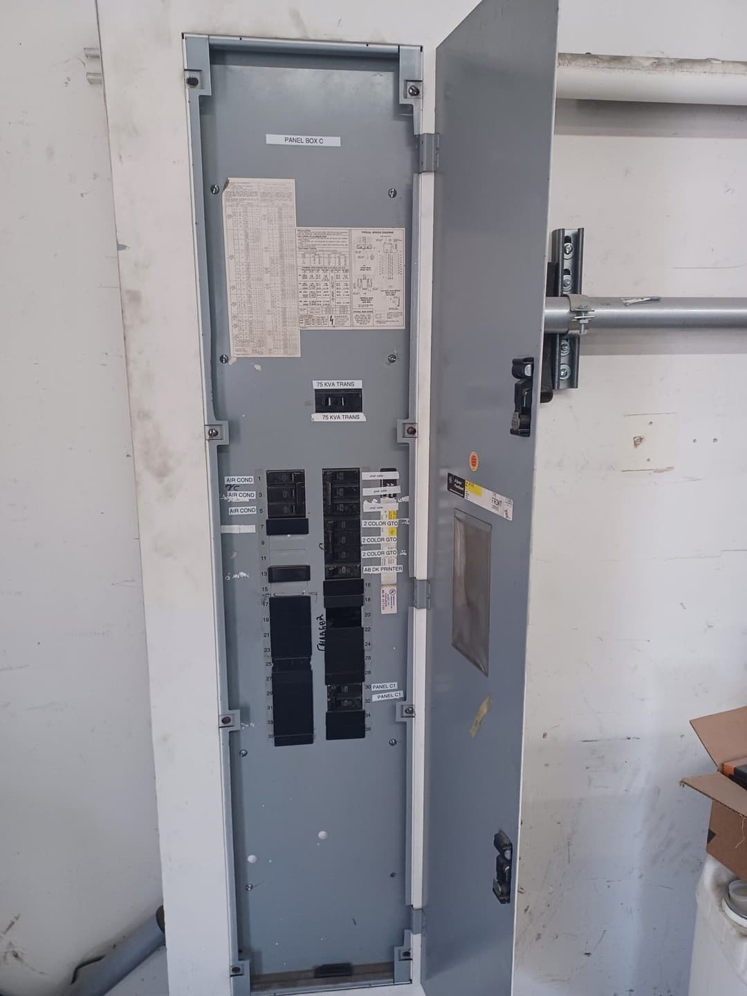 Electrical panel with circuit breakers and a labeled diagram, mounted on a wall.