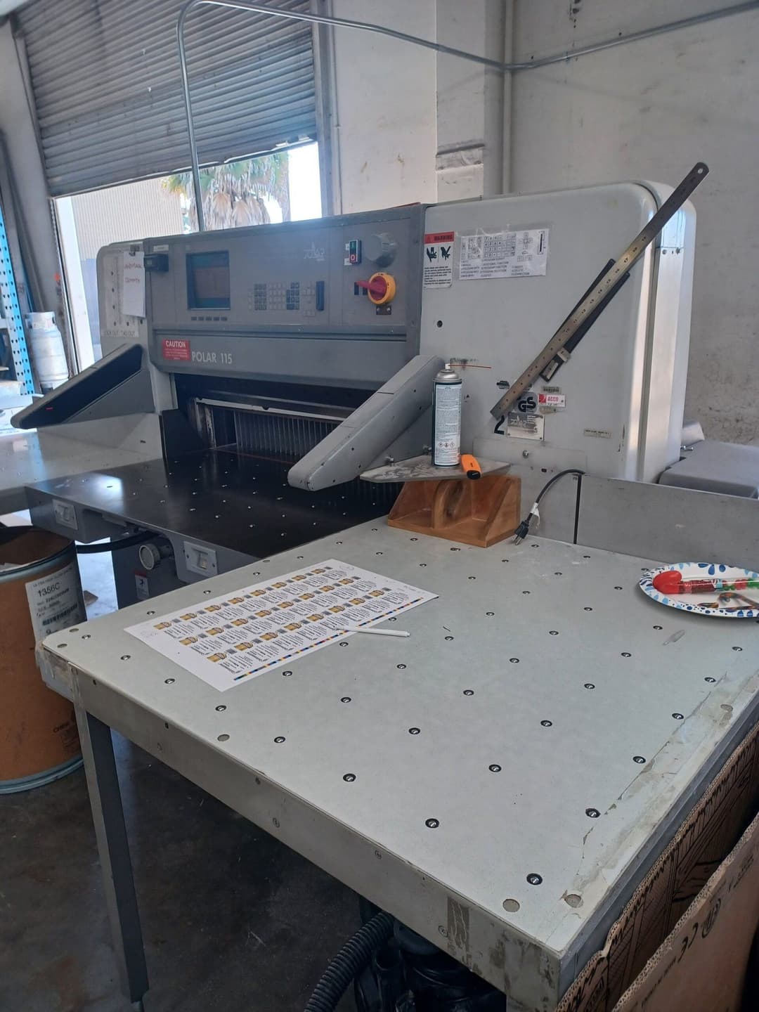 Commercial Polar 115 paper cutter on a workbench in a printing facility.